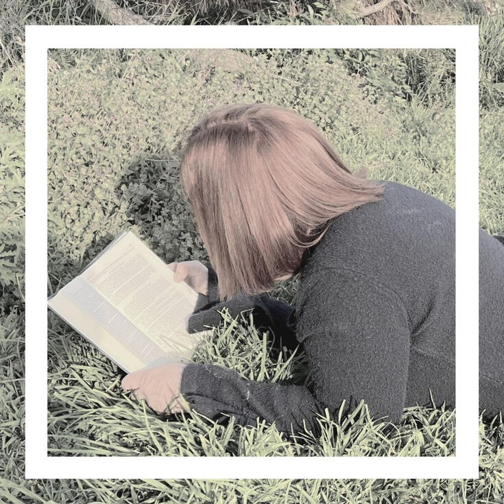 Freddie Astra logo and square photo of girl laying on grass reading a book